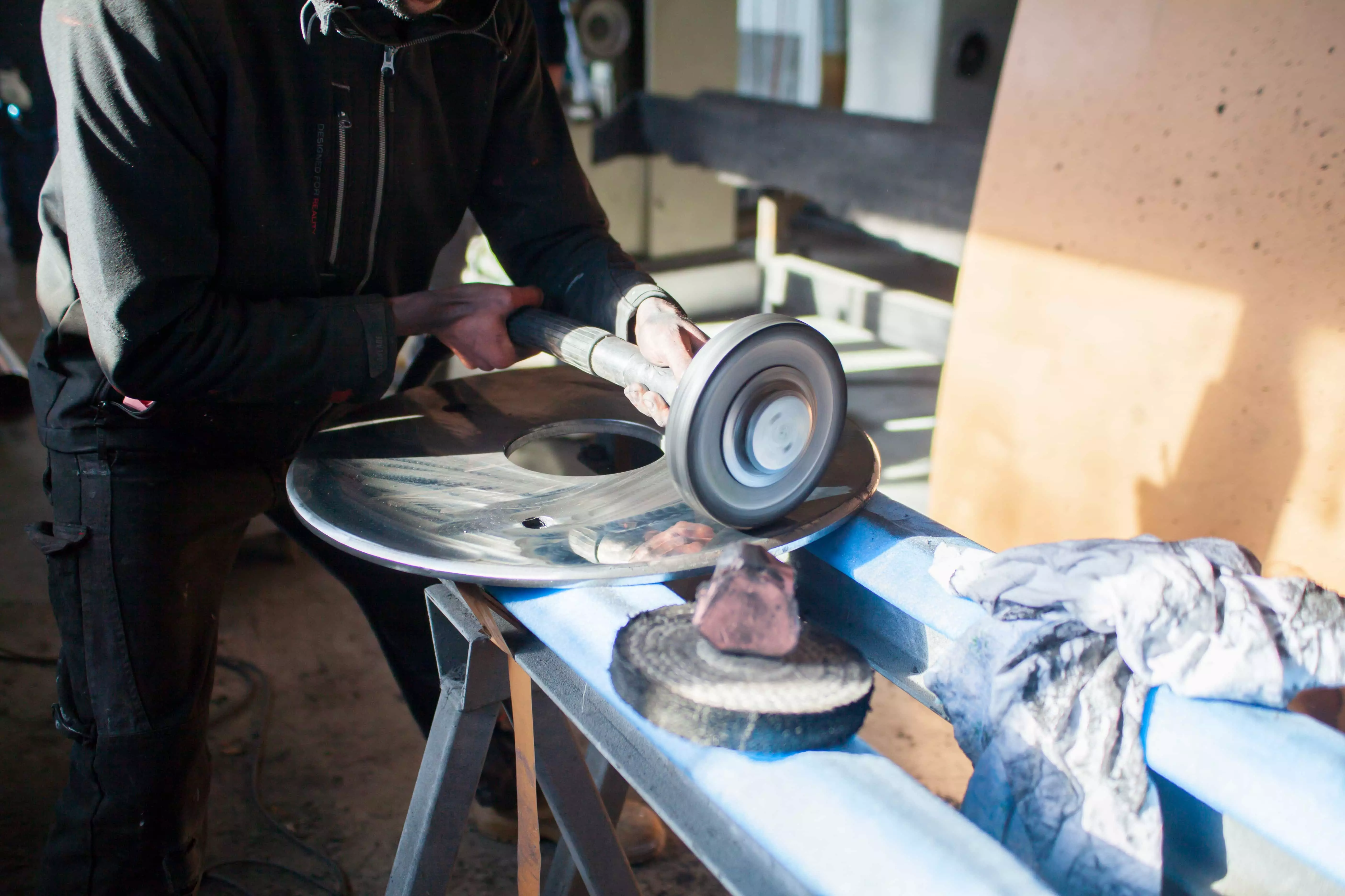 Photo du making of du telescope, ici un ouvrier poli un grand disque en métal